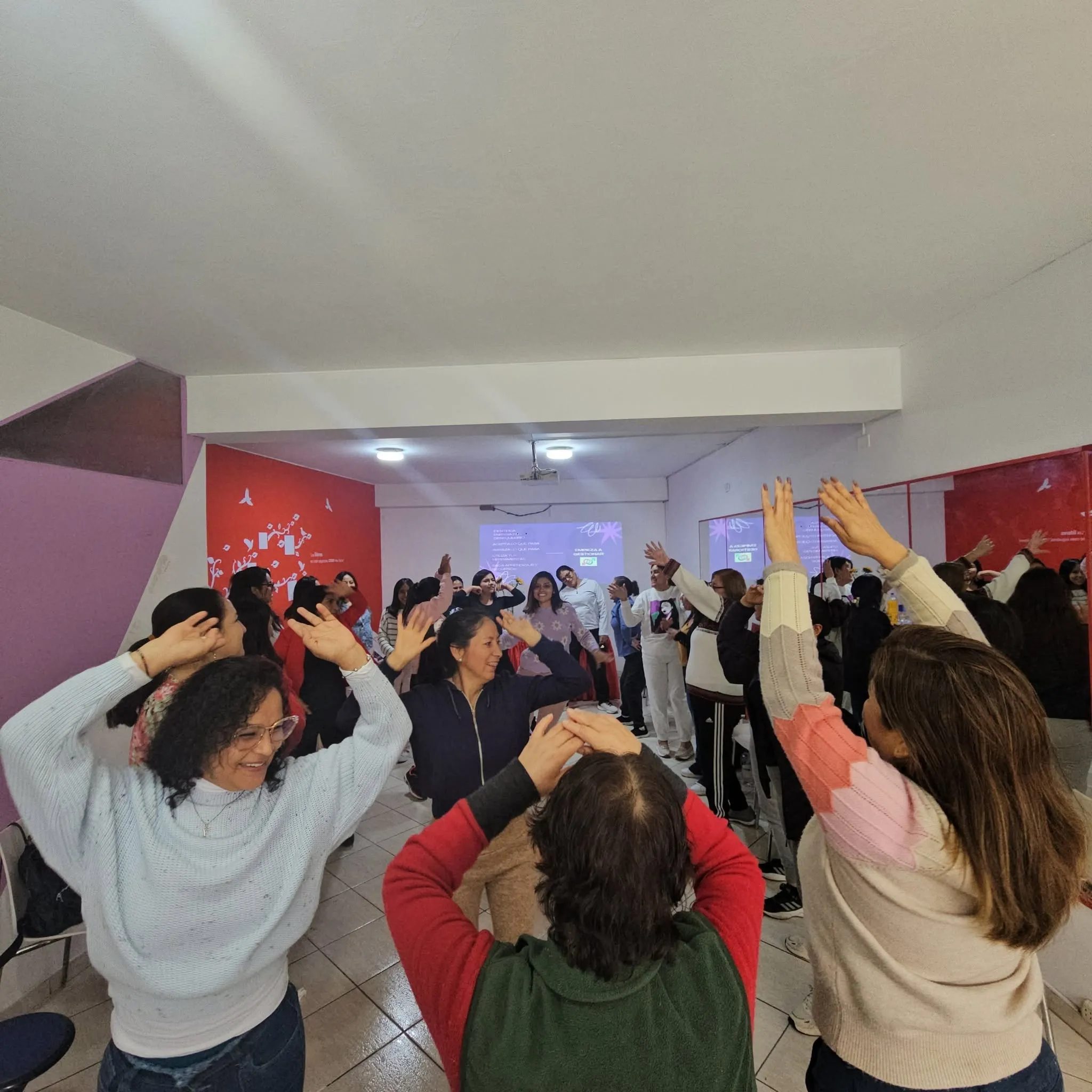 Participantes realizan una dinámica grupal con las manos levantadas